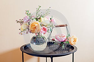 Fresh bouquet of roses flowers put in glass vase on table. Close up of pink yellow blooms with basket. Interior decor