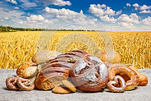 Fresh bread and bakery on sackcloth against the background wheat field