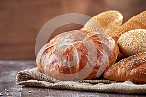 Fresh bread on a cloth linen with brown background on the wooden table with flour