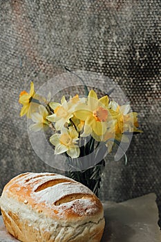 fresh bread only from the oven, cools down on parchment paper, near beautiful flowers