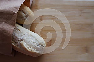 Fresh bread in a paper bag lies on a wooden background with a place for text. selectiv focus