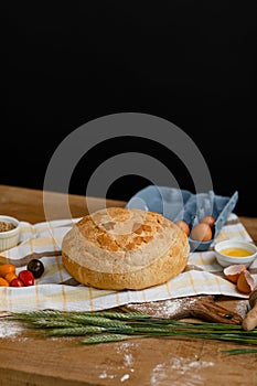 Fresh bread placed on a towel together with tomatoes and eggs. Bakery - gold rustic crusty loaves of bread