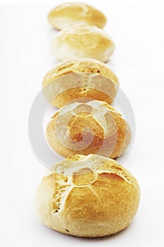 Fresh bread rolls in a row, isolated on white.