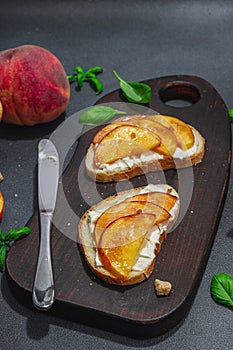 Fresh bread sandwiches with sweet peach slices, cream cheese and basil leaves. Good morning concept