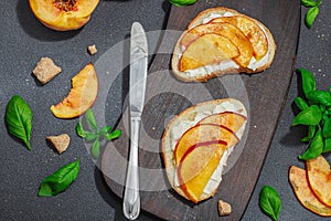 Fresh bread sandwiches with sweet peach slices, cream cheese and basil leaves. Good morning concept