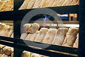 Fresh bread on shelves stand of a shop or bakery. Freshly baked bread loaves at window of store front. Organic pastry. Space for