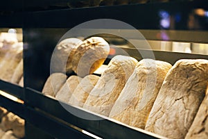 Fresh bread on shelves stand of a shop or bakery. Freshly baked bread loaves at window of store front. Organic pastry. Space for