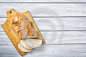 Fresh bread slices on cutting board against white grey wooden background. Top view