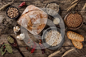 Fresh bread, spice and cereals selection in bowls on rustic wooden background. Healthy food concept, top view, flat lay