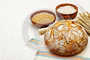 Fresh bread with wheat ears and a bowls of flour and grain