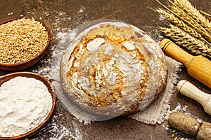 Fresh bread with wheat ears and a bowls of flour and grain