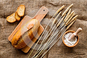 Fresh bread with wheat flour in bakery shop on linen desk background top view