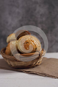 Fresh bread in a wicker basket on canvas napkin on wooden table