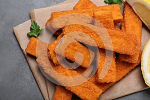 Fresh breaded fish fingers served on grey table, top view