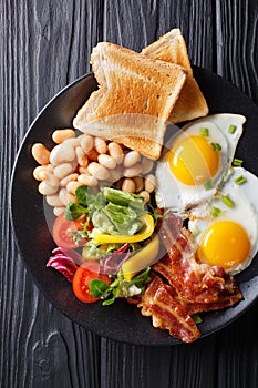 Fresh breakfast: fried eggs with bacon, beans, toast and vegetab