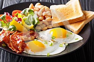 Fresh breakfast: fried eggs with bacon, beans, toast and vegetab