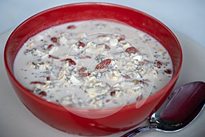 Fresh breakfast of granola, yogurt, nuts, goji berries, chia seeds and banana. Muesli with fruits and berries in red bowl