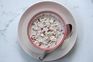 Fresh breakfast of granola, yogurt, nuts, goji berries, chia seeds and banana. Muesli with fruits and berries in red bowl