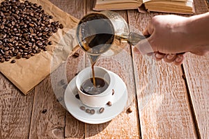 Fresh breved coffe in cezve traditional turkish coffee pot Woman`s hand pours coffee into white cup