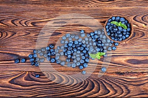 Fresh and bright blueberries. Healthy, ripe, raw and bright dark blue berries on a wooden background. Copy space. Summer fruits.