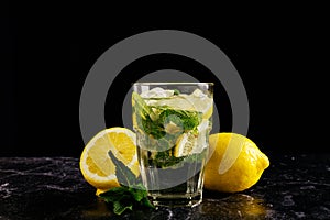 Fresh bright summer cocktail. Mojito cocktail with lemon and mint in a glass on a fashionable stone black background