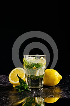 Fresh bright summer cocktail. Mojito cocktail with lemon and mint in a glass on a fashionable stone black background