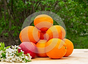 Fresh bright tasty oranges with white flowers on a wooden table in the garden, natural vegan food