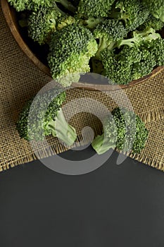 Fresh Broccoli in wooden bowl and seed oil in rustic style. Close up on a black background. copy space for text. Top