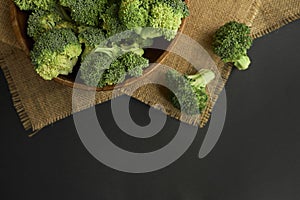 Fresh Broccoli in wooden bowl and seed oil in rustic style. Close up on a black background. copy space for text. Top