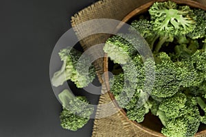 Fresh Broccoli in wooden bowl and seed oil in rustic style. Close up on a black background. copy space for text. Top