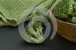Fresh Broccoli in wooden bowl and seed oil in rustic style. Close up on a black background. side view, harvest