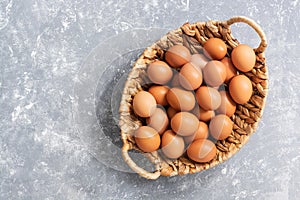 Fresh brown eggs in a basket on a gray background. View from above, flat lay.Copy space