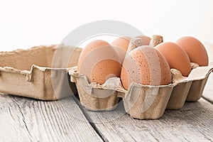 Fresh brown eggs in carton on wooden table