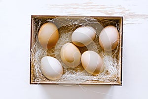 Fresh brown eggs and some straw in a wooden crate