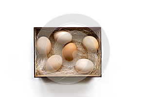 Fresh brown eggs and some straw in a wooden crate