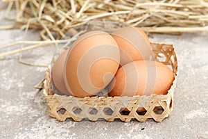 Fresh brown eggs in wicker bowl isolated. Pile of raw chicken egg on rice straw background
