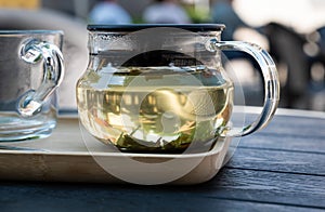 Fresh brown green tea in a glass mug on a wooden terrace table in summer, Belgium photo