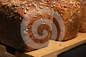 fresh brown loaves of rye bread in the form of bricks with sunflower seeds on a crust. Lie on a wooden rack