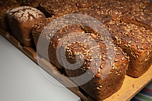 fresh brown loaves of rye bread in the form of bricks with sunflower seeds on a crust. Lie on a wooden rack