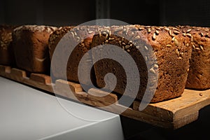 fresh brown loaves of rye bread in the form of bricks with sunflower seeds on a crust. Lie on a wooden rack