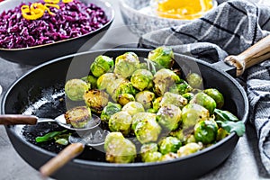 Fresh brussels sprouts in black iron pan on grey table