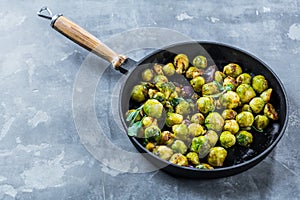 Fresh brussels sprouts in black iron pan on grey table