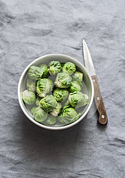 Fresh brussels sprouts in white bowl on grey background
