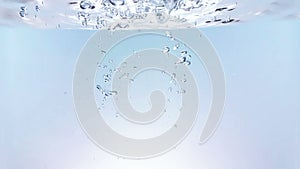 Fresh bubbles splash falling down into water, shot in slow motion on white background, purity and clean, nutrition and health care