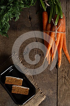 Fresh bunch of carrots on old wood background adn carrots cakes
