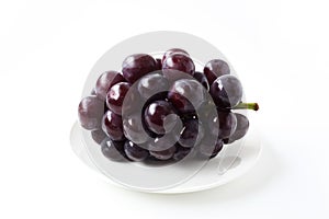 Fresh bunch of grapes on plate isolated on white background