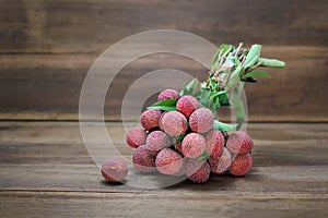 Fresh bunch of lychee fruit Litchi chinensis on wooden background.