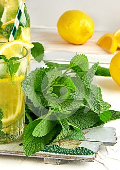 fresh bunch of mint and a glass with lemonade on a wooden board