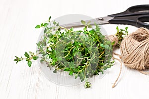 Fresh bunch of thyme and kitchen scissors on white table