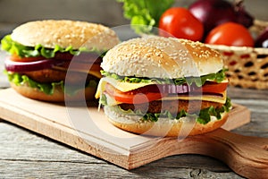 Fresh burgers on cutting borad on wooden background